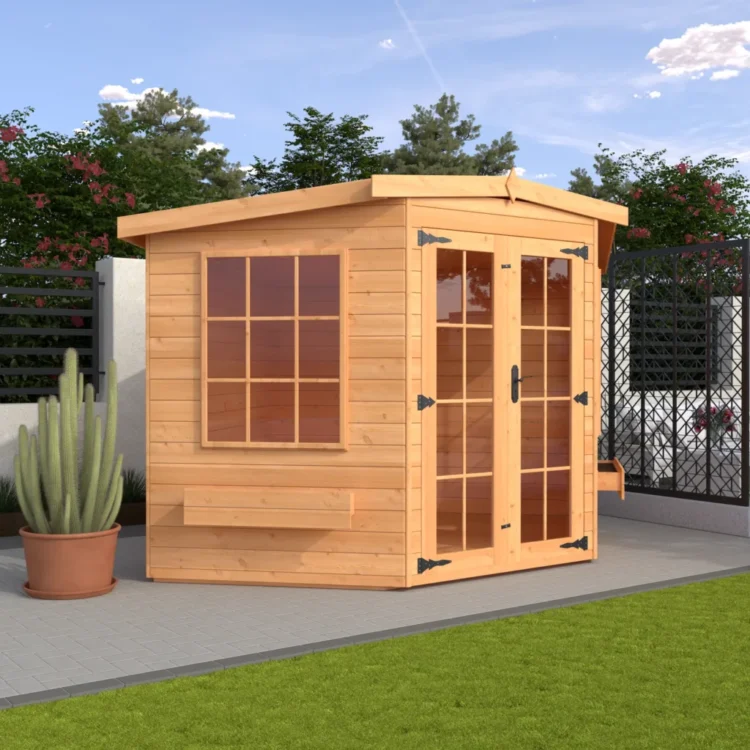 A light wooden shed with glass doors and window on a patio, surrounded by green grass and plants under a blue sky