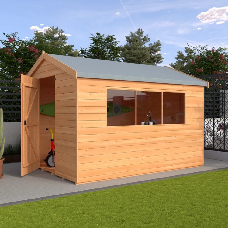 A wooden shed with a grey roof and open door on a patio in a garden with green grass and trees