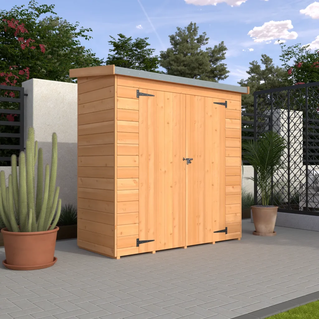 A wooden shed with double doors on a patio surrounded by plants and a fence under a blue sky