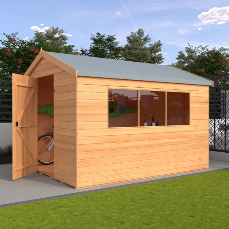 A wooden shed with light brown horizontal slats and grey roof on a patio with a bicycle inside and green lawn and trees outside